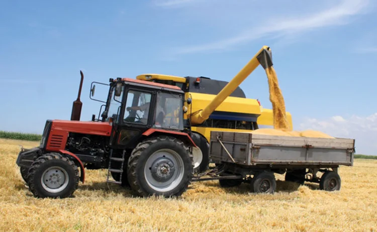 A tractor and combine harvester harvesting grain