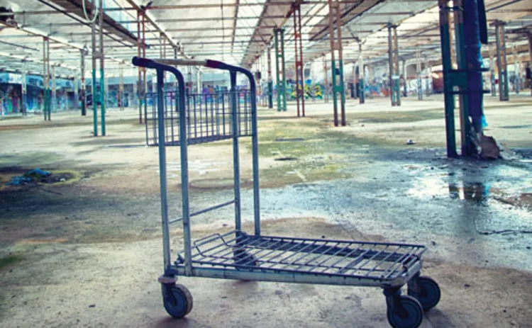 An unoccupied warehouse building with an abandoned trolley in it