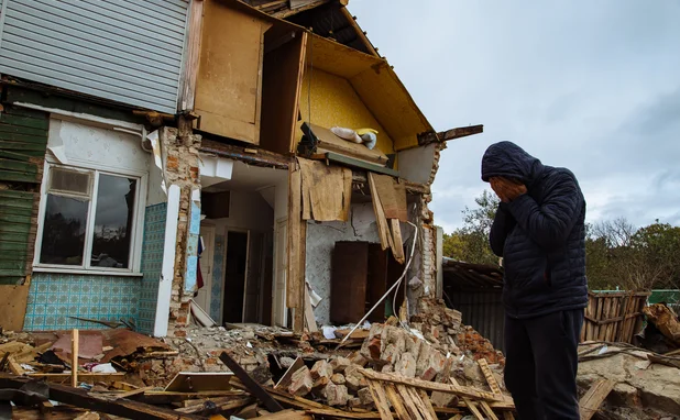 Sad man on ruined house. Hopeless, homelessness, result of military conflicts and natural disasters concept.