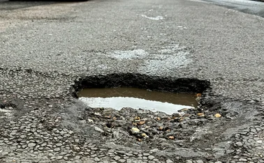 A deep, water filled pothole in a shopping street in Eastbourne, East Sussex, UK.