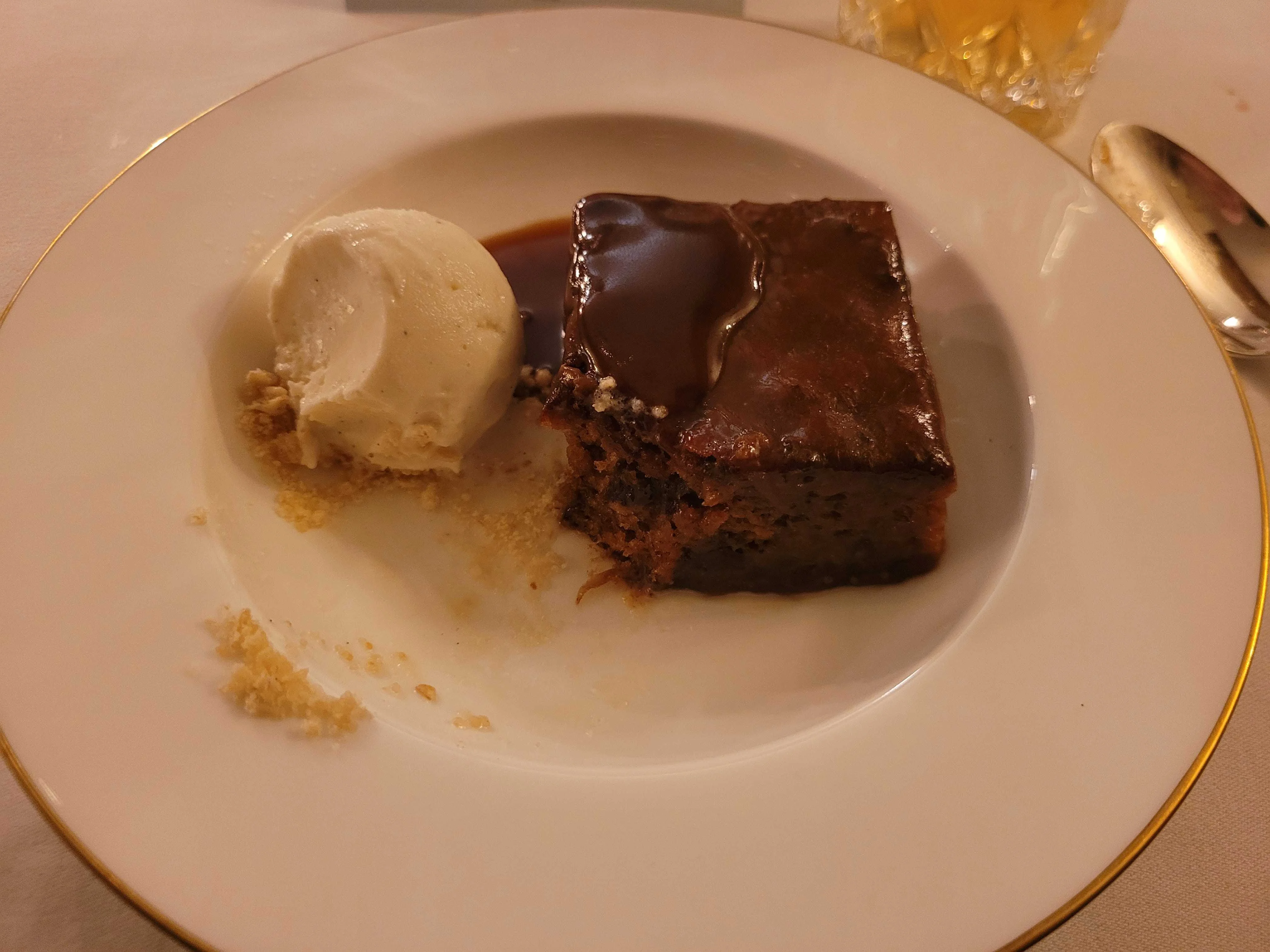 A plate of sticky toffe pudding with a bite taken out of it.
