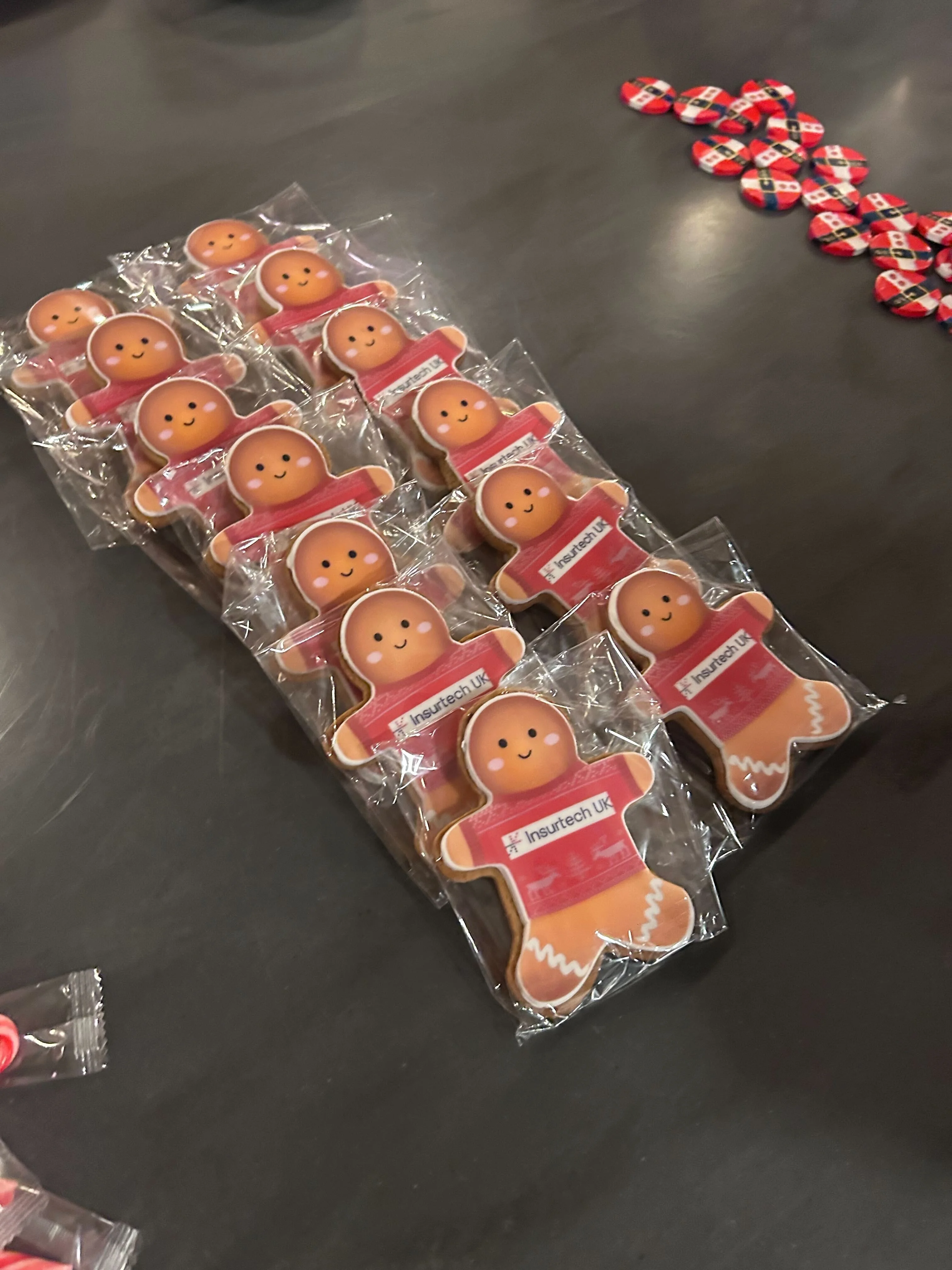 Insurtech UK branded gingerbread men laid out on a black table.