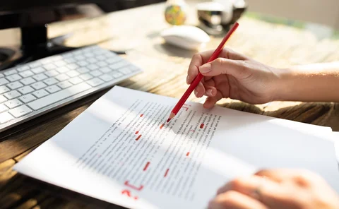 Close-up Of A Person's Hand Marking Error With Red Marker On Document