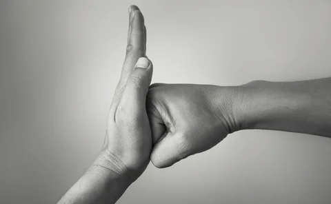 Hand preventing stopping punch attack of another hand.