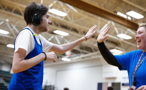 Neurodivergent man high fives his coach 