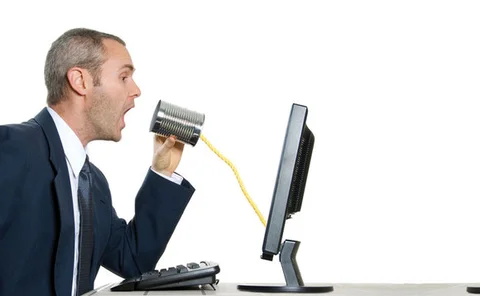 Two men sitting infront of computers communicating via tin can and string