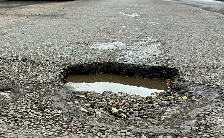 A deep, water filled pothole in a shopping street in Eastbourne, East Sussex, UK.