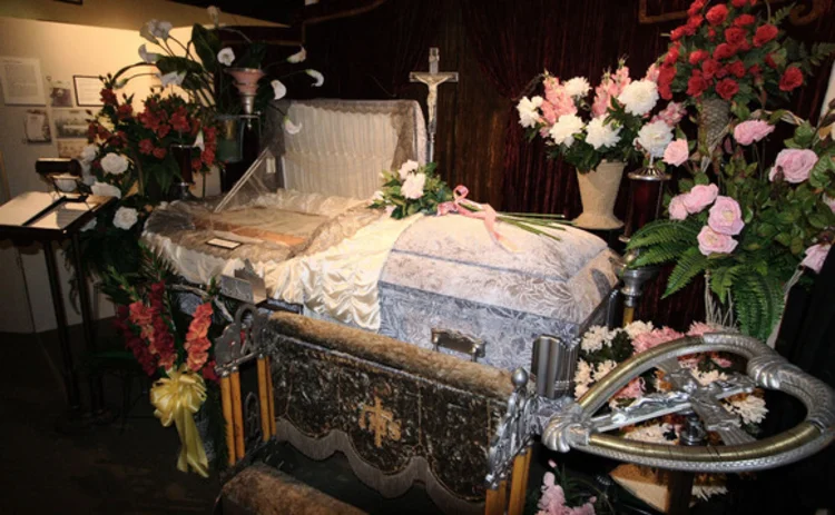 An open coffin surrounded by flowers