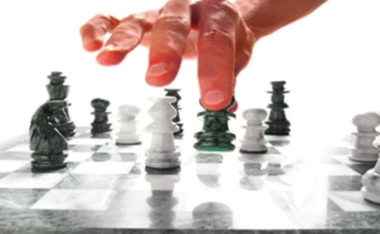 A hand moving chess pieces on a board