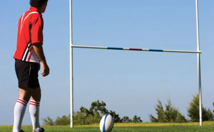 A rugby player lining up a kick at goal