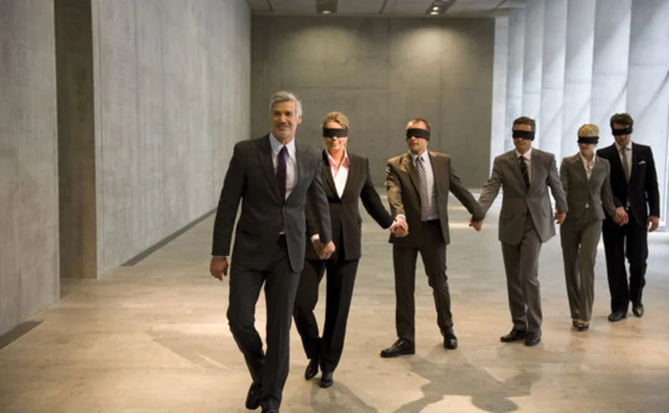 A businessman leading blindfolded colleagues