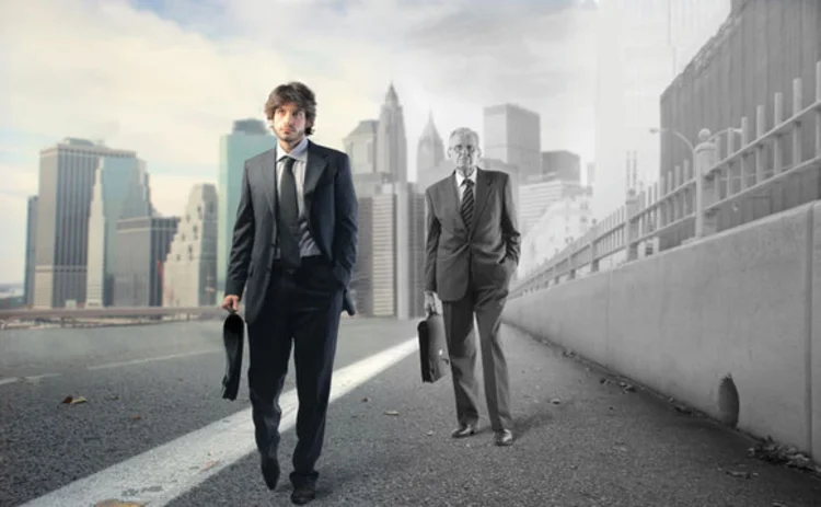 A young businessman walking ahead of an older businessman