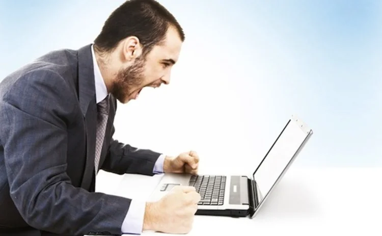 An angry man shouting at a laptop