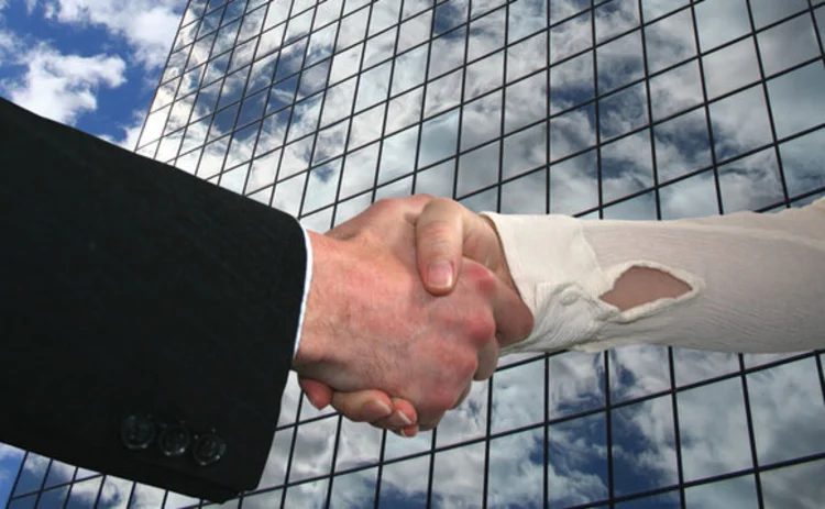 Handshake in front of a skyscraper reflecting clouds