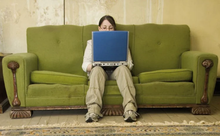 A child on a sofa using a laptop