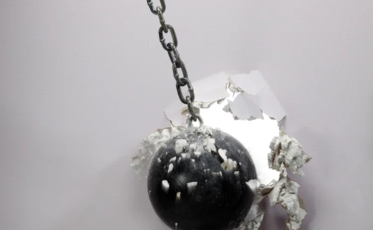 A wrecking ball breaking a white wall
