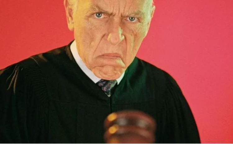 Judge with stern expression pointing gavel