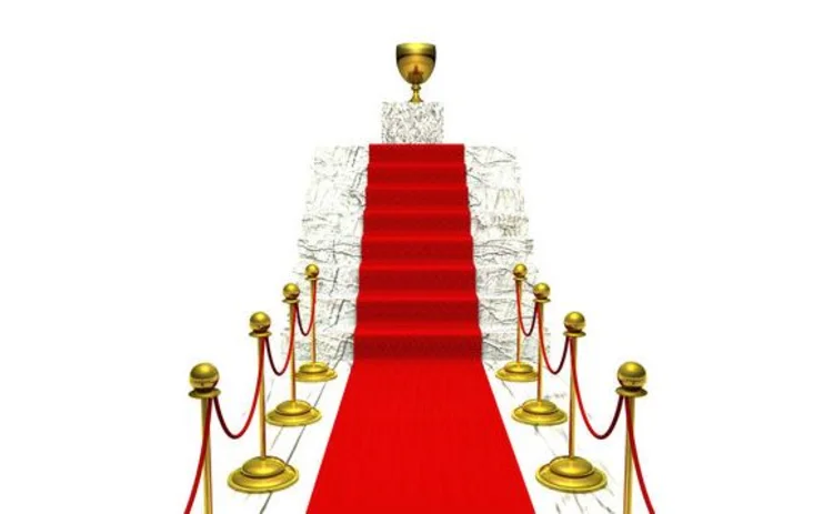 Cordoned off red carpet up stairs leading to gold trophy