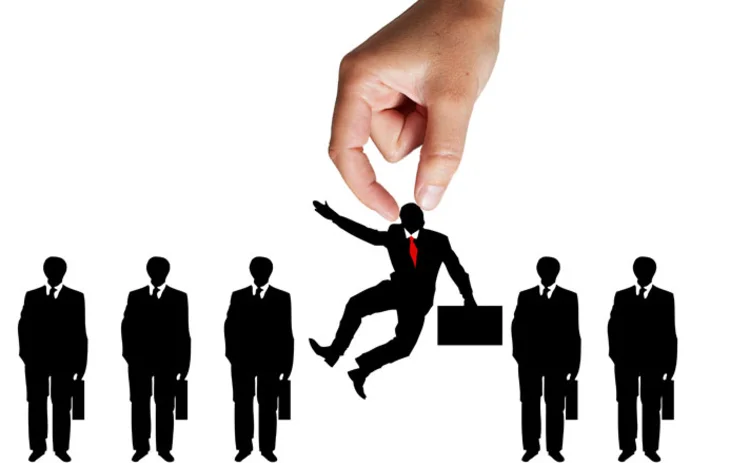 A hand appearing from above a line of job candidates and picking one