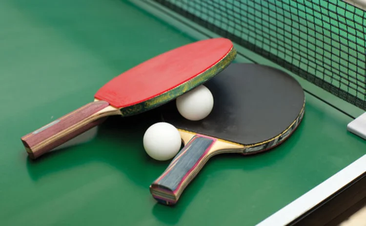 Two table tennis paddles and balls on a ping pong table