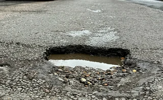 A deep, water filled pothole in a shopping street in Eastbourne, East Sussex, UK.
