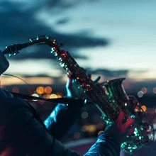 Close-up shot of female musician playing a saxophone on a rooftop at evening