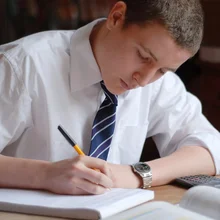 15 year old boy studying at the kitchen table.