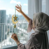 A young Asian Muslim girl holding an Eid Mubarak decoration on the house window at home during Ramadan.